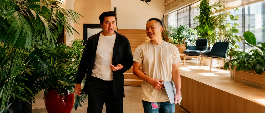 Two colleagues walking and talking through a bright office