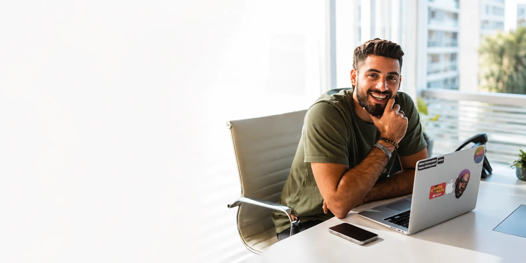 A learner smiling at his desk beside an open laptop