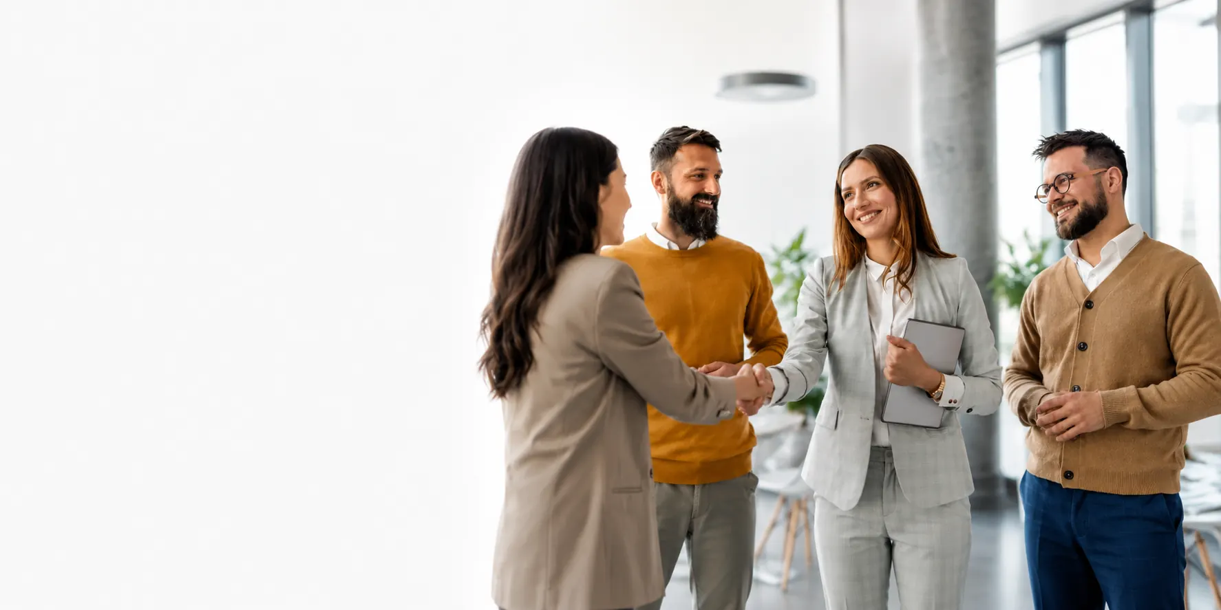 Two teams meeting and shaking hands in a bright office